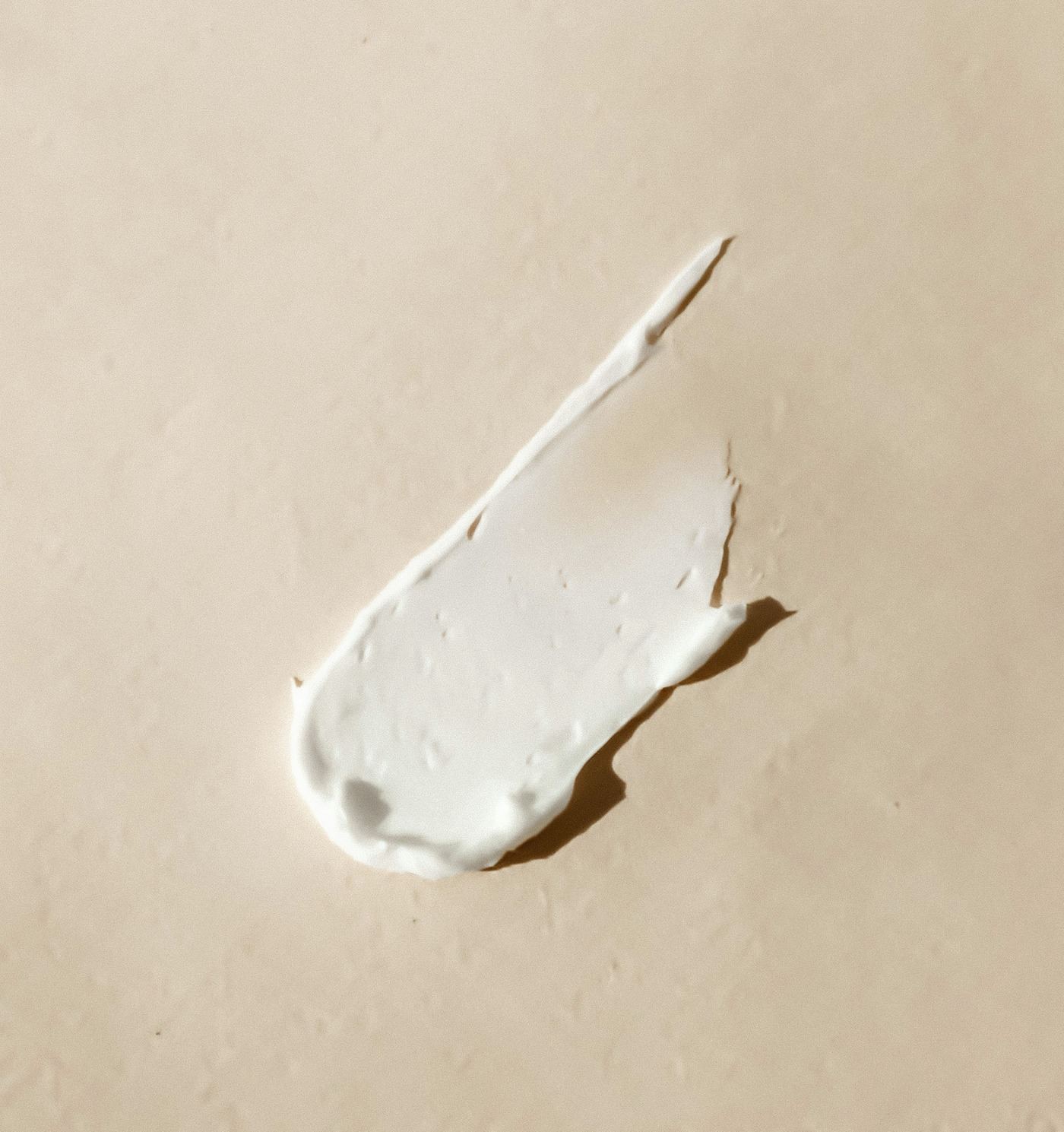 A swatch of white cream on a warm beige surface
