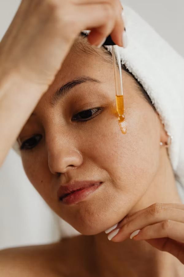A woman applying a golden serum with a dropper
